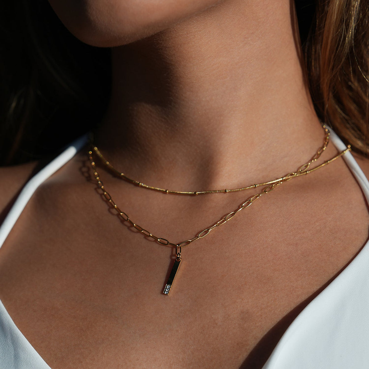 Style KORATIA : Collier Minimaliste avec Chaîne Trombone et Pendentif Barre Ornée de Zirconium Doré