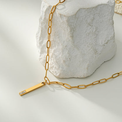Style KORATIA : Collier Minimaliste avec Chaîne Trombone et Pendentif Barre Ornée de Zirconium Doré