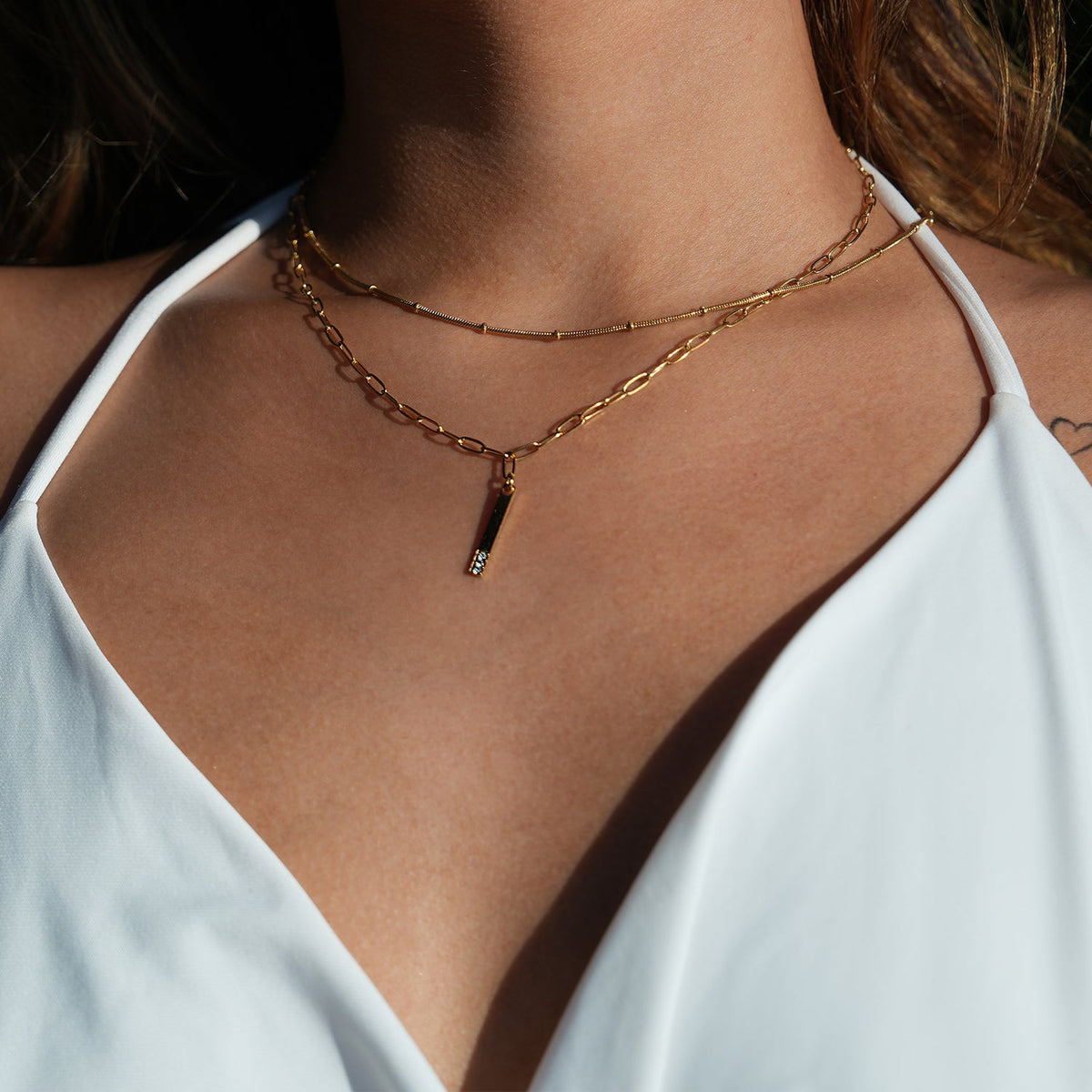 Style KORATIA : Collier Minimaliste avec Chaîne Trombone et Pendentif Barre Ornée de Zirconium Doré